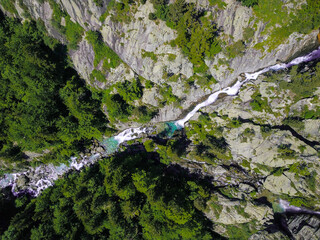 Aerial drone view of a waterfall in a river with turquoise water located in a green natural environment in Pyrenees, Spain.
