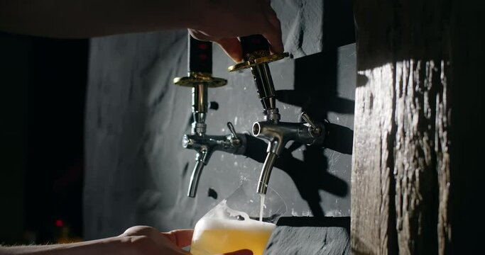 Barman pours unfiltered light beer from the beer tap to the glass in slow motion, pouring wheat beer in the pub, 4k 120fps Prores HQ