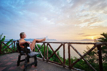 Fototapeta na wymiar Traveling by Thailand. Young woman enjoying wonderful sunset on Phuket island view point.