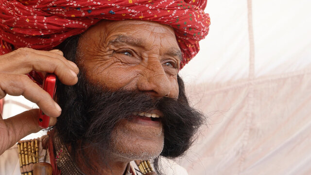 Closeup Of An Elderly South Asian Man With A Thick Mustache And A Pagri Talking On The Phone