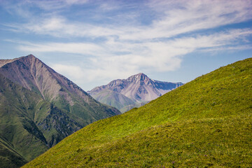 Beautiful Summer landscape: blue cloudy sky, green hills and distant mountains