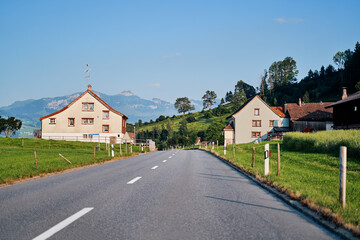 Fototapeta na wymiar Asphalt road in Alps mountain village. Road trip concept.