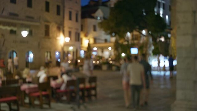 Lively evening square in a small old European town. Summer terraces of cafes and restaurants, cozy atmosphere. People travel, relax and walk in the old city. Blured shot, 4K