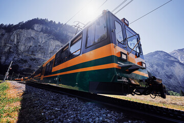 Beautiful mountains landscape. Yellow-green train running through the Swiss Grindelwald Village, Switzerland.