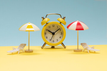 Time to travel. Sun lounger, yellow umbrella and alarm clock.