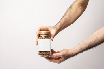 Hands holding an instant coffee glass jar with blank label isolated on gray background