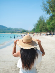 Woman white dress with hat on the beach and blue water sea and many people and valley in nature background,Tourism concept on the beach vacation