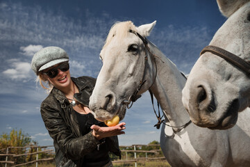 Portrait of female feeding white purebred  horse