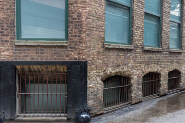 Corner of vintage brick building with steel post window covers in alley