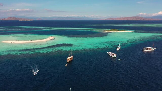 Aerial drone footage of the taka makassar sandbar near Komodo in Labuan Bajo, Flores, Indonesia with some traditional cruise ship anchored off the reef. 