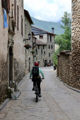 Detail of healthy woman riding her bike through the stone houses and woods of Anciles, a village nearby Benasque, one of the most amazing spots of the Spanish Pyrenees mountains.