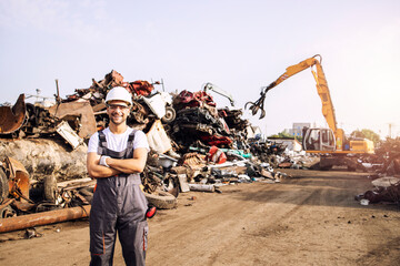 Portrait of junkyard worker standing in scrap metal recycling center. - obrazy, fototapety, plakaty