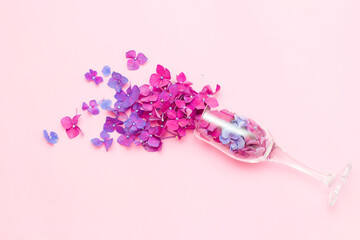 A champagne glass with spring flowers on a pink background, the concept of a party in a minimal season. The idea of the flowering of nature. Purple and pink flowers