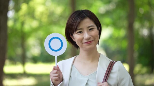 頷いて〇札を出す女性社員