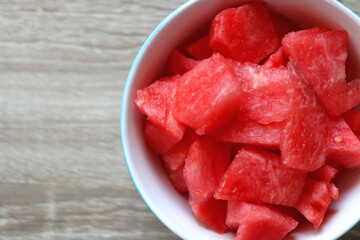 Bowl of watermelon cubes on wooden table. Flat lay.