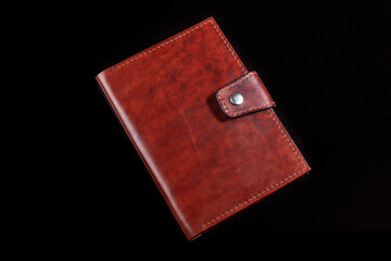 Leather wallet brown wallet with a button fastener on a dark background.