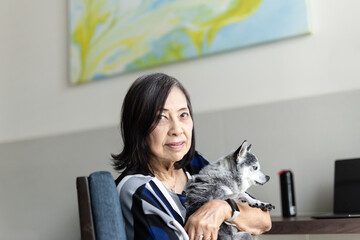 Senior woman holding cute small chihuaha dog.