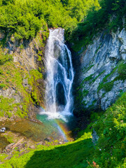 Beautiful secret wild waterfall with a rainbow in a green environment in Pyrenees.