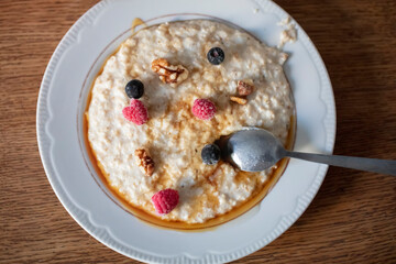 Oatmeal on a wooden background with berries and nuts.