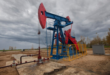 Fototapeta na wymiar An oil rig pumps oil against the backdrop of a beautiful sky. Oil industry.
