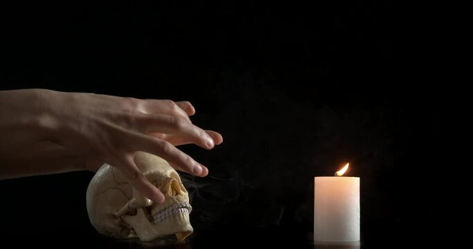 Doing magic with a skull. A female doing magic with a skull and candle in the room in the dark.