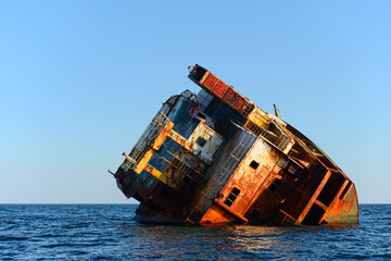 The rusting remains of the hull of a stranded ship in the open sea