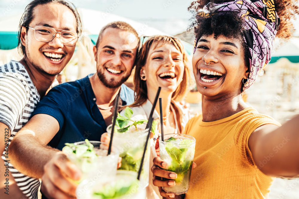 Wall mural young people toasting mojito drinks at beach cocktail bar - happy multiracial friends having fun tak