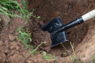 An iron shovel in a hole in the ground. Hand earthworks.
