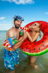 young woman and man with a beard and a diving mask stand in the sea in the summer with an inflatable ring