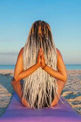 young woman doing yoga on the beach on the sand in the summer