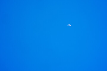 crescent moon on sunny day against blue sky background.