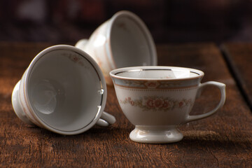Porcelain cups, beautiful porcelain cups arranged on rustic wood, dark background, selective focus.