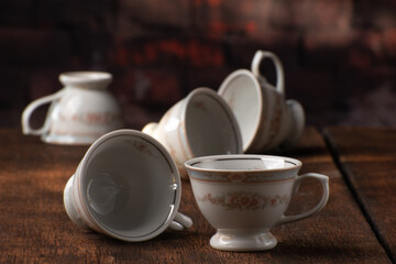Porcelain cups, beautiful porcelain cups arranged on rustic wood, dark background, selective focus.