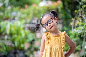 Happy little girl with glasses standing at garden.