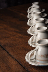 Porcelain cups, beautiful porcelain cups geometrically arranged on rustic wood, dark background, selective focus.
