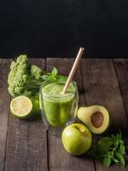 Fresh green smoothie in glass on wooden table, closeup.  Detox diet concept: green vegetables on rustic table. Clean eating, alkaline diet, weight loss food concept.