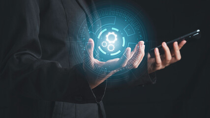 Digital workflow, Digital transformation, Automatic technology concept. Businessman holding digital machine gears  icons in cyber circle and holding smartphone.