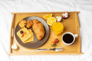 Breakfast in a tray filled with black Coffee, Cheese and chocolate croissant with orange juice with few strawberries