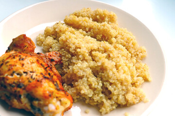 A piece of baked chicken with porridge on a plate.