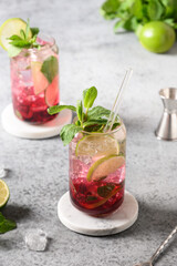 Blueberries mojito with lime, mint and ice cube on gray background. Vertical format.