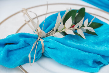 White banquet table covered with blue cloth, served with plates, cutlery, glasses, candles and flower arrangements. Top view. Copy, empty space for text