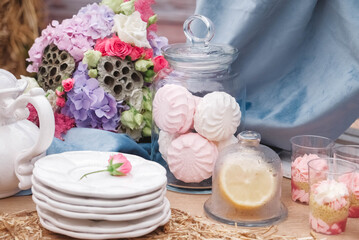 Fototapeta na wymiar Wedding candy bar in rustic style decorated with plates, cutlery, glasses, candles and flower arrangements. Copy, empty space for text