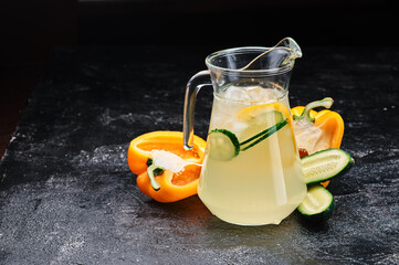 Summer healthy lemonade with cucumber and lime in decanter on black background. Space for text....