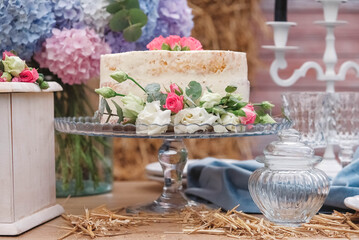 White wedding cake decorated by flowers standing of festive table. Copy, empty space for text