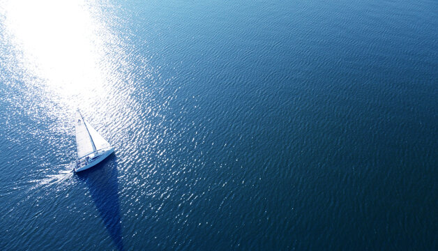 Aerial view of a white yacht with a sail. Ship in the blue sea