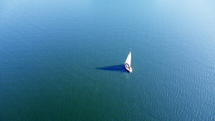 Aerial view of a white yacht with a sail. Ship in the blue sea