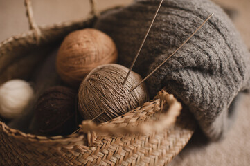 Yarn balls with knit cloth fabric and .knitting needles in straw basket in room. Winter season....