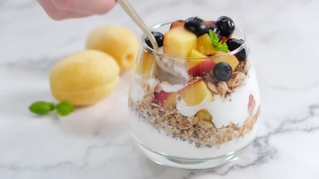 Eating healthy yogurt granola parfait with a spoon. Clean eating, dietig concept