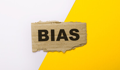On a white and yellow background, brown torn cardboard with the text BIAS