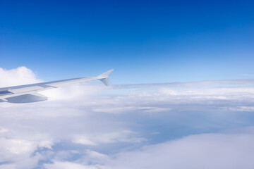 blue sky with clouds and the wing of a flying plane